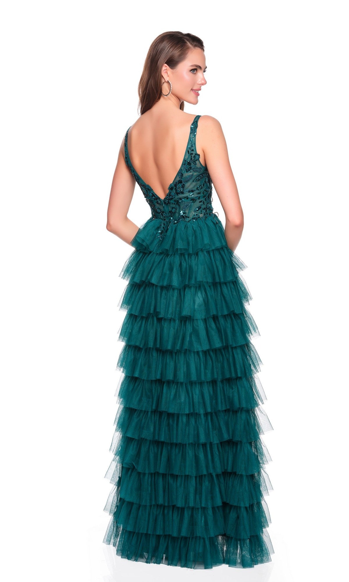 A woman models the Dave and Johnny 12635 long prom dress, featuring an embroidered bodice, deep V-back, and dramatic floor-length green tiered tulle skirt, standing against a white background.